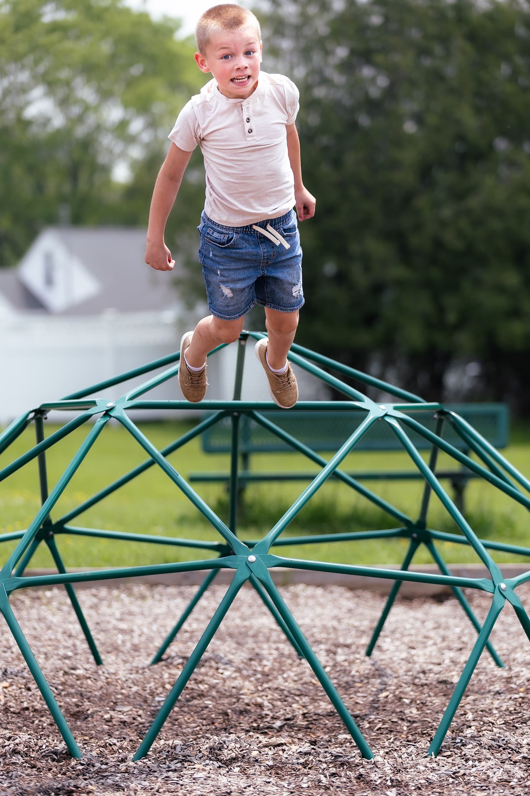 Boy jumping on playground climbing dome