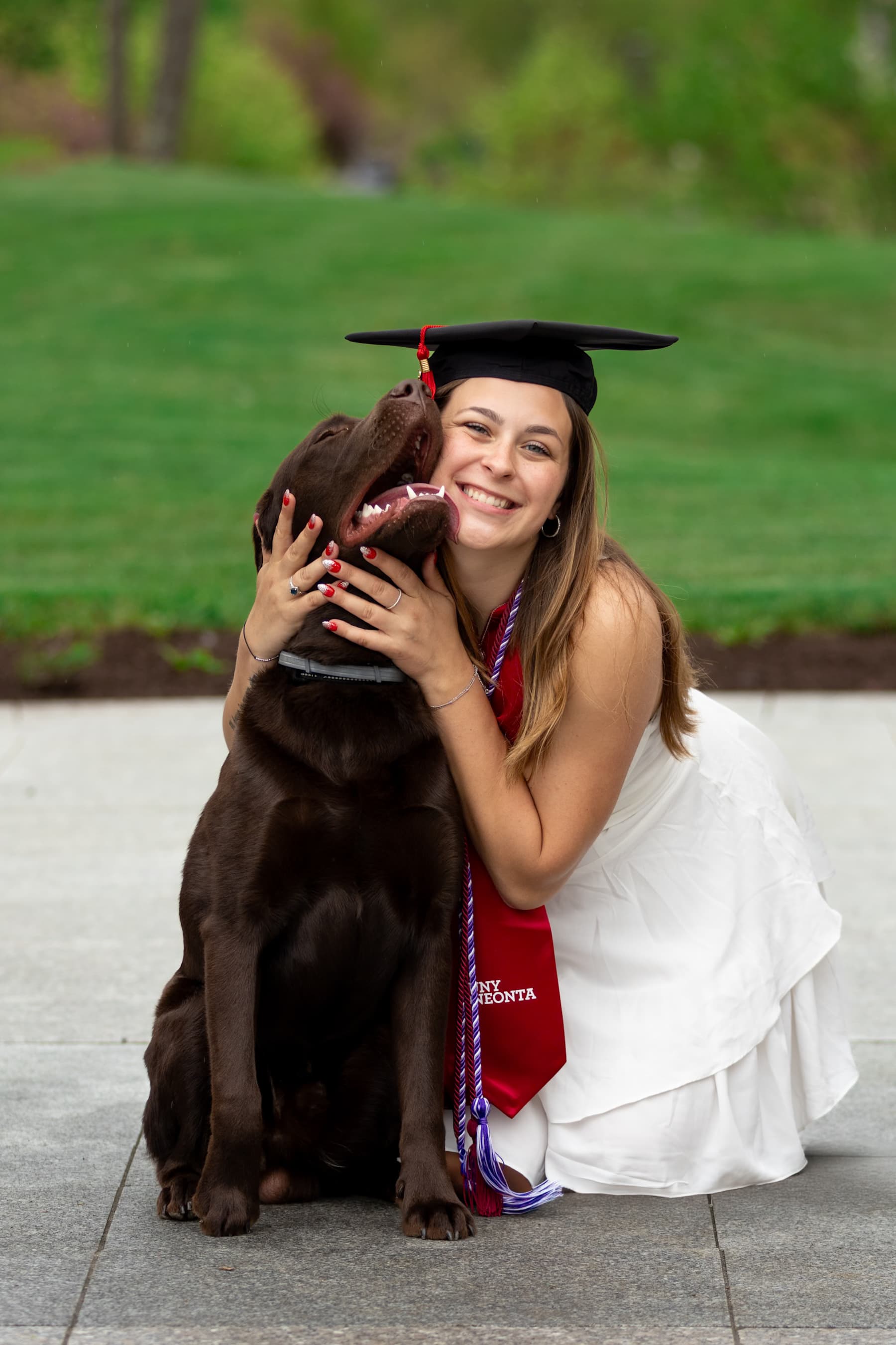 Graduate hugging her chocolate lab